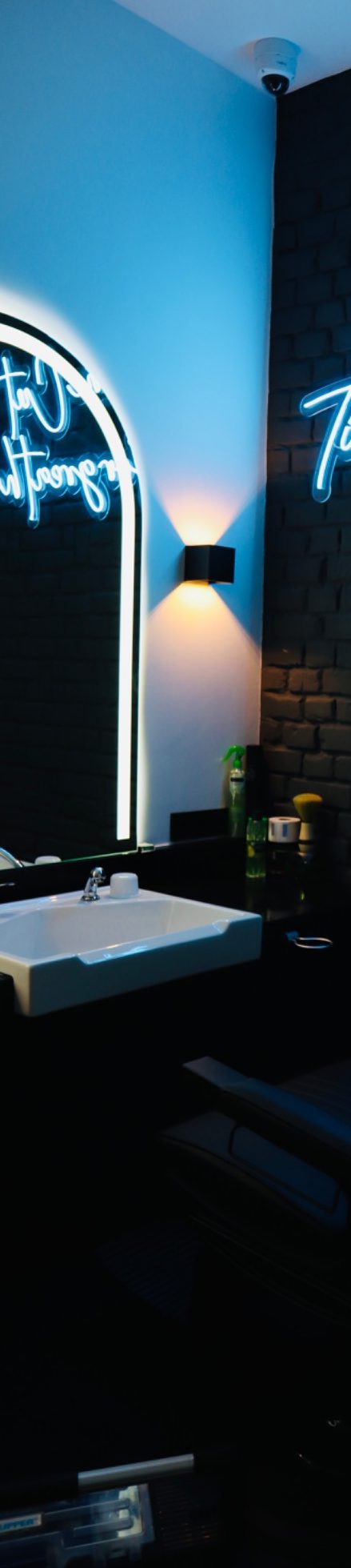 Moderne stilvoller Herrenfriseur mit blauen Wänden, beleuchtetem Spiegel und eleganten Möbeln.