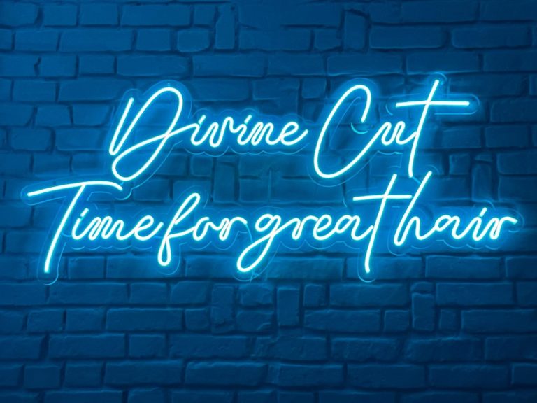 Neon-Schriftzug "Divine Cut - Time for great hair" auf einer steinernen Wand. Barbershop Frankfurt