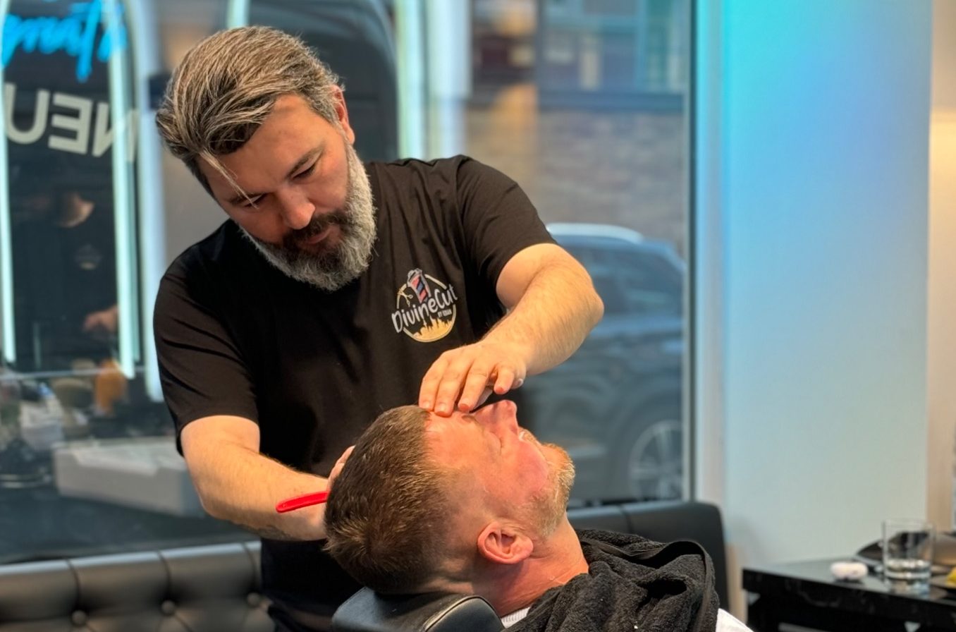 Friseur vollzieht eine Nassrasur eines Mannes in einem modernen Friseuralon.